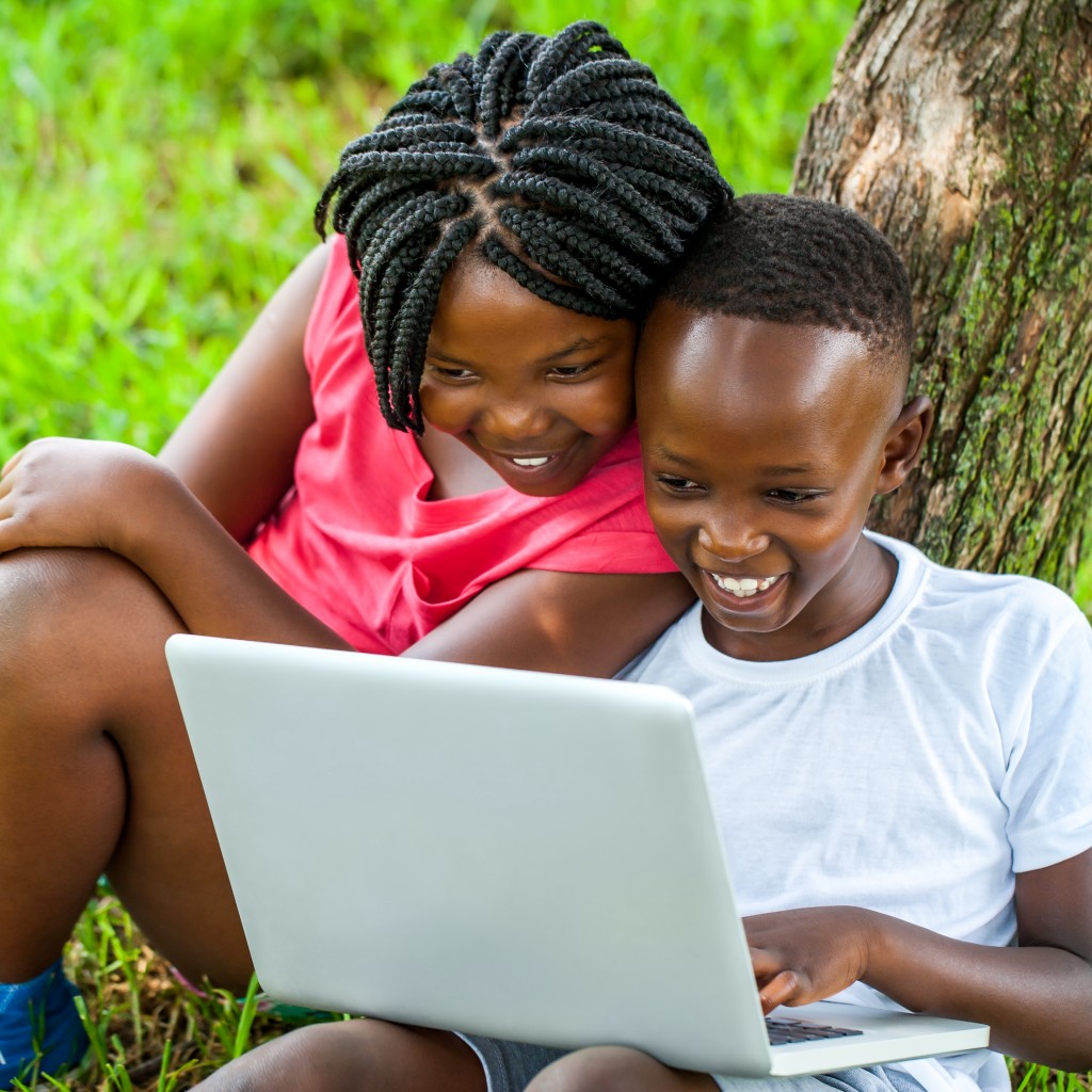 African boy and girl playing on laptop.